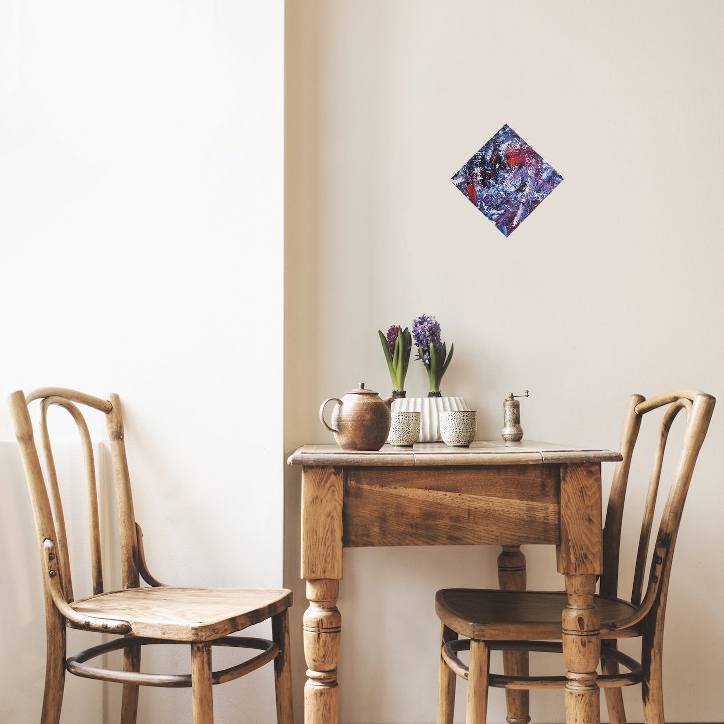 L'image représente un tableau abstrait aux couleurs principales violet et bleu, avec des touches de rouge et de blanc. Ses dimensions sont de 30 cm par 30 cm, affiché pointe en haut comme un losange. Il a été créé à la peinture à l'huile avec un travail au couteau. Il présente des empâtements et des reliefs, des traits expressifs. Le tableau a été peint à la peinture à l'huile par la peintre autodidacte Maeva J.