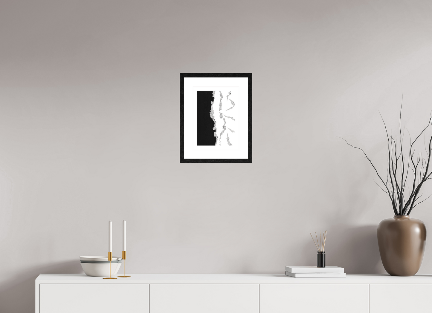 L'image représente un tableau abstrait à l'encre noire sur fond blanc. C'est une oeuvre de l'artiste peintre Maeva J., son titre est "Eclore". Elle est présentée dans un cadre noir accroché au mur.