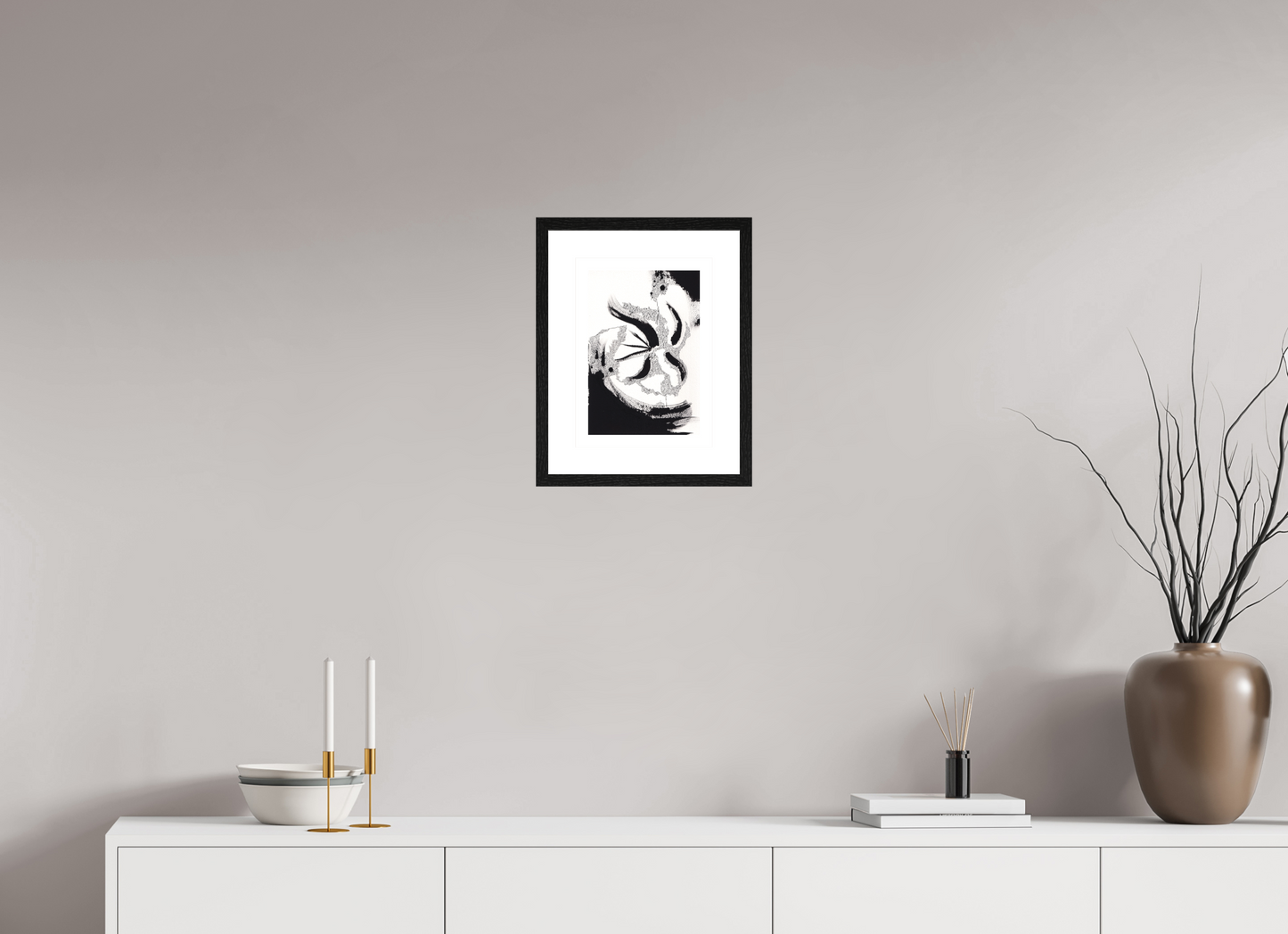 L'image représente un tableau abstrait à l'encre noire sur fond blanc. C'est une oeuvre de l'artiste peintre Maeva J., son titre est "Volition". Elle est présentée dans un cadre noir accroché au mur.