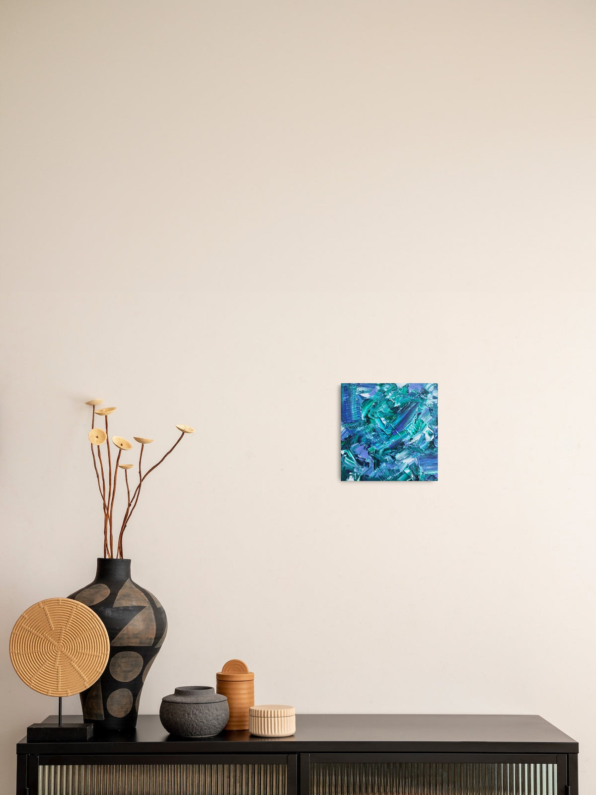 L'image représente un tableau abstrait aux couleurs principales bleu et vert, avec des touches de blanc. Ses dimensions sont de 20 cm par 20 cm. Il a été créé à la peinture à l'huile avec un travail au couteau. Il présente des empâtements et des reliefs, des traits expressifs. Le tableau a été peint à la peinture à l'huile par la peintre autodidacte Maeva J.