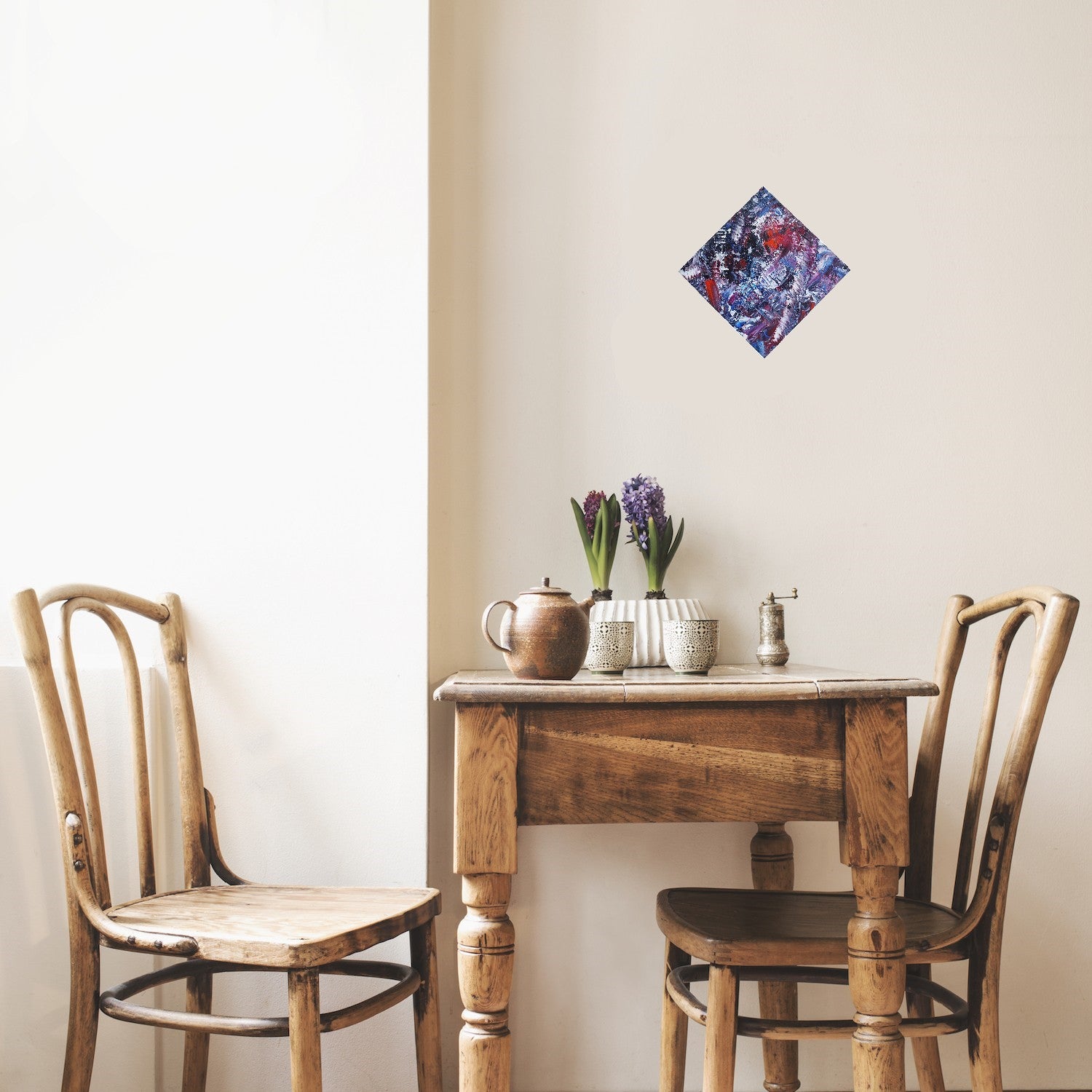 L'image représente un tableau abstrait aux couleurs principales violet et bleu, avec des touches de rouge et de blanc. Ses dimensions sont de 30 cm par 30 cm, affiché pointe en haut comme un losange. Il a été créé à la peinture à l'huile avec un travail au couteau. Il présente des empâtements et des reliefs, des traits expressifs. Le tableau a été peint à la peinture à l'huile par la peintre autodidacte Maeva J.
