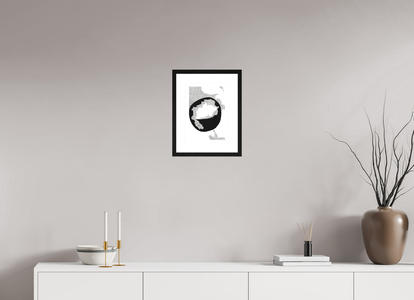 L'image représente un tableau abstrait à l'encre noire sur fond blanc. C'est une oeuvre de l'artiste peintre Maeva J., son titre est "Conscience". Elle est présentée dans un cadre noir accroché au mur.
